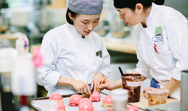 A 91Porn baking instructor and student look over pink pastries